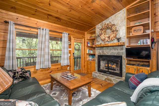 living room with a stone fireplace, wood-type flooring, lofted ceiling, built in features, and wooden walls