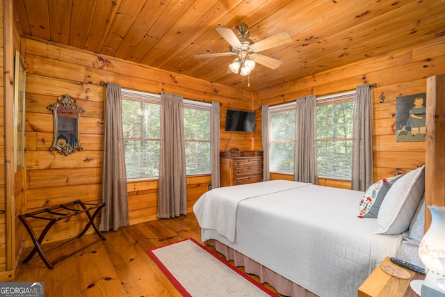 bedroom featuring ceiling fan, hardwood / wood-style flooring, wood ceiling, and wood walls