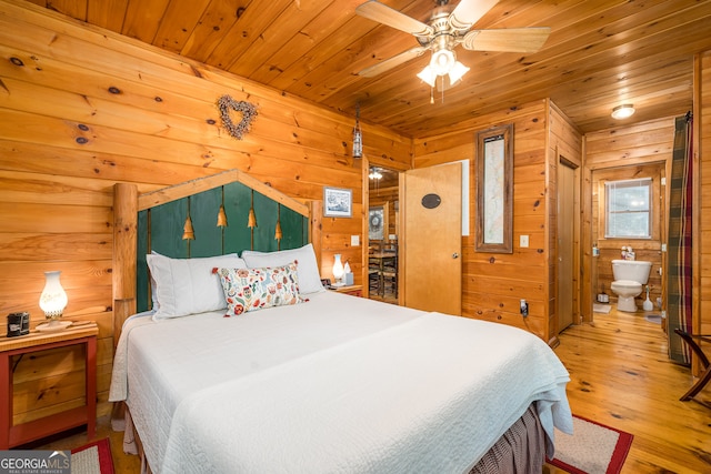 bedroom featuring ceiling fan, wood walls, wooden ceiling, light wood-type flooring, and ensuite bathroom