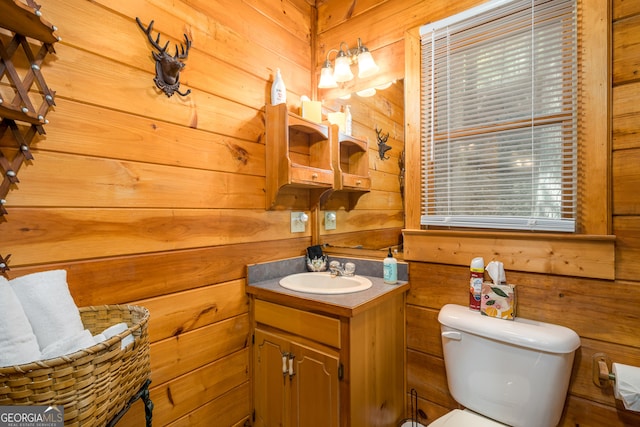 bathroom with vanity, wooden walls, and toilet