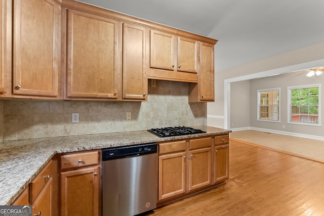 kitchen with light wood-type flooring, dishwasher, black gas stovetop, light stone countertops, and ceiling fan