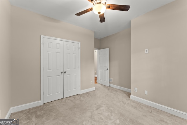 unfurnished bedroom featuring ceiling fan, light colored carpet, and a closet