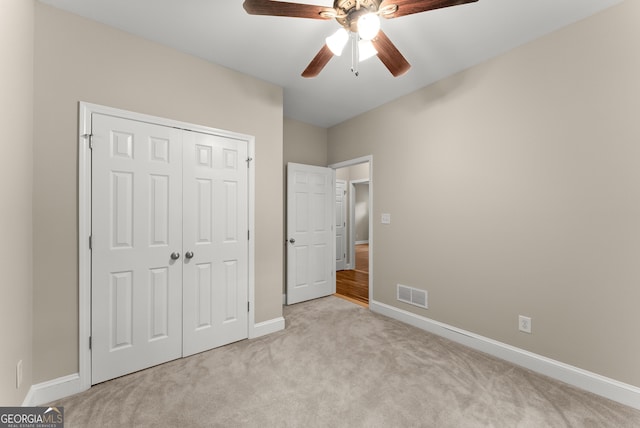 unfurnished bedroom with light carpet, a closet, and ceiling fan