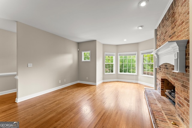 unfurnished living room with light hardwood / wood-style flooring and a brick fireplace