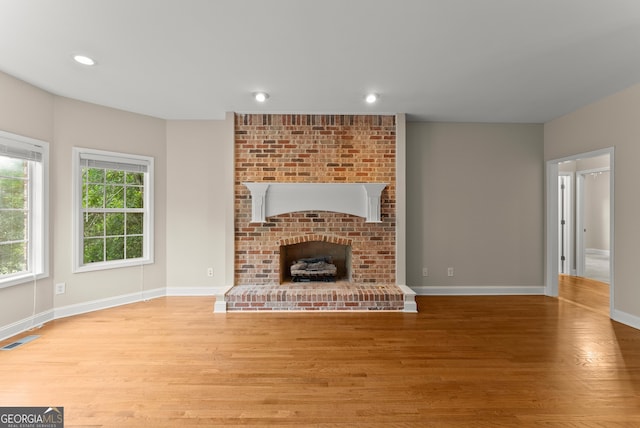 unfurnished living room with a fireplace and light hardwood / wood-style floors