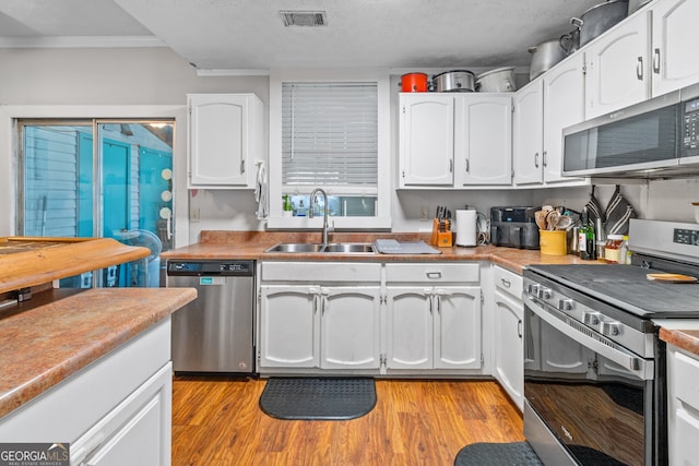 kitchen with appliances with stainless steel finishes, white cabinets, sink, and a textured ceiling