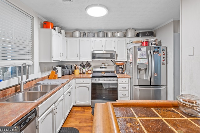 kitchen featuring stainless steel appliances, crown molding, sink, white cabinets, and a textured ceiling