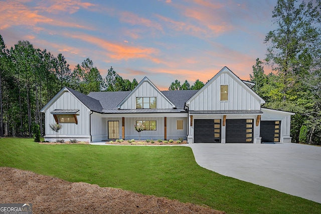 modern farmhouse style home featuring a garage, a lawn, and covered porch