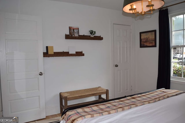 bedroom with multiple windows, an inviting chandelier, and hardwood / wood-style flooring