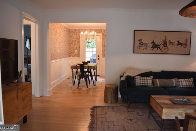 living room with wood-type flooring, an inviting chandelier, and crown molding