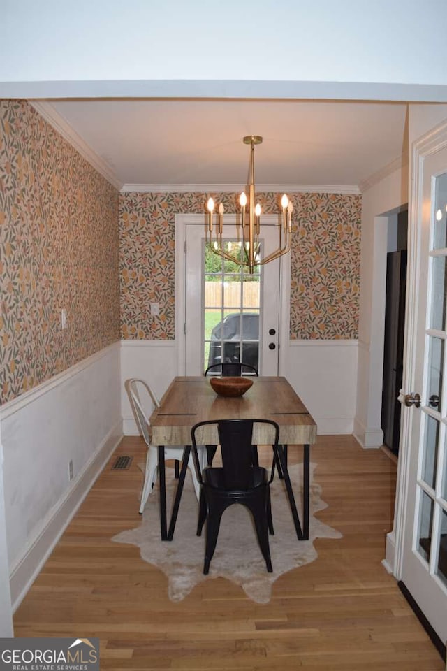 dining room with wood-type flooring, crown molding, and a chandelier