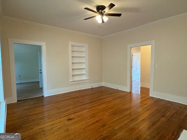 spare room featuring crown molding, built in shelves, dark hardwood / wood-style flooring, and ceiling fan