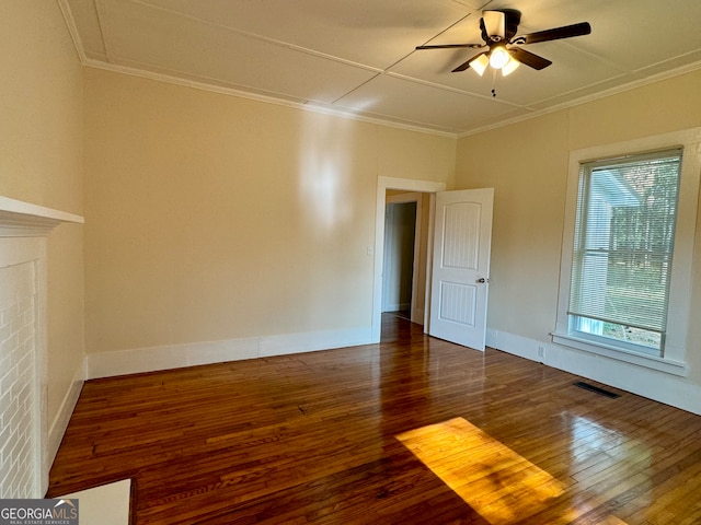 spare room with ceiling fan, dark hardwood / wood-style floors, a fireplace, and crown molding