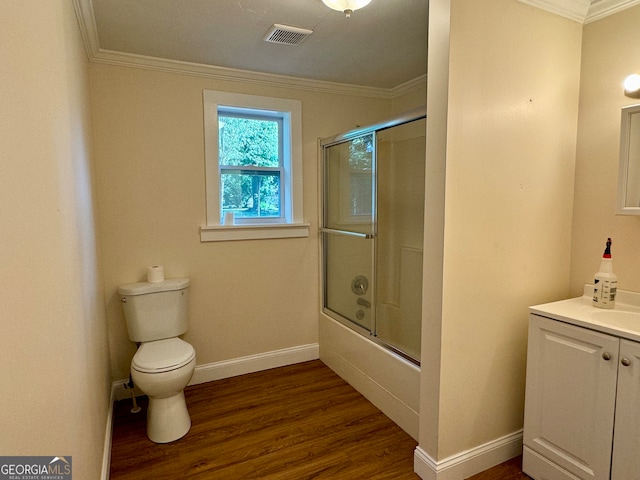 full bathroom featuring vanity, crown molding, combined bath / shower with glass door, toilet, and hardwood / wood-style floors