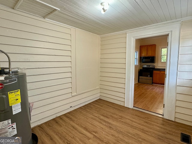 interior space featuring wood ceiling, wood-type flooring, water heater, and wood walls