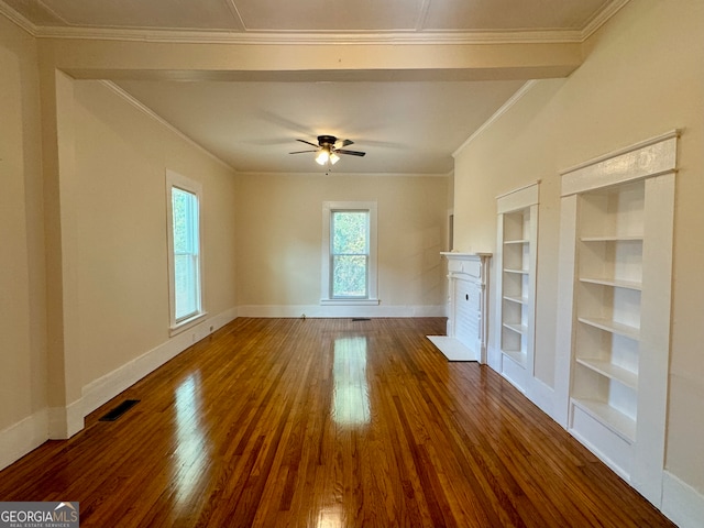 unfurnished living room featuring built in shelves, ceiling fan, dark wood-type flooring, and crown molding