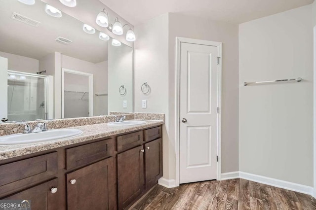 bathroom with wood-type flooring, vanity, and a shower with door