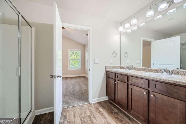 bathroom featuring walk in shower, vanity, lofted ceiling, and wood-type flooring