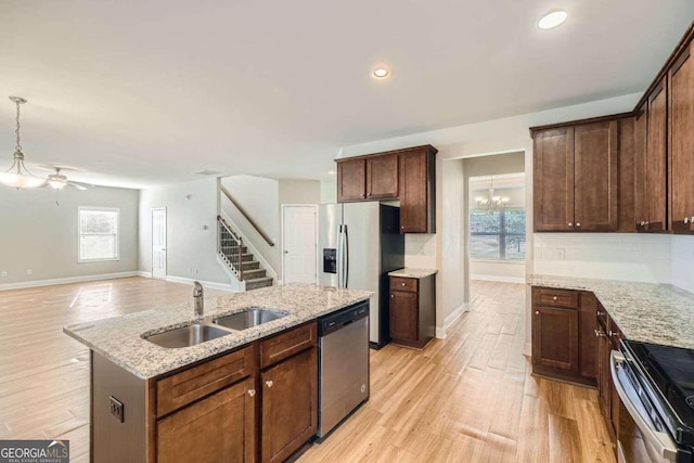 kitchen featuring sink, stainless steel appliances, a kitchen island with sink, and light hardwood / wood-style floors