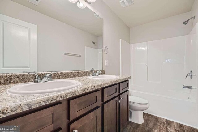 full bathroom featuring hardwood / wood-style flooring, shower / bath combination, vanity, and toilet