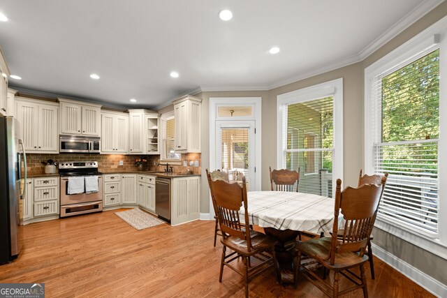 kitchen featuring stainless steel appliances, light wood-type flooring, ornamental molding, and tasteful backsplash