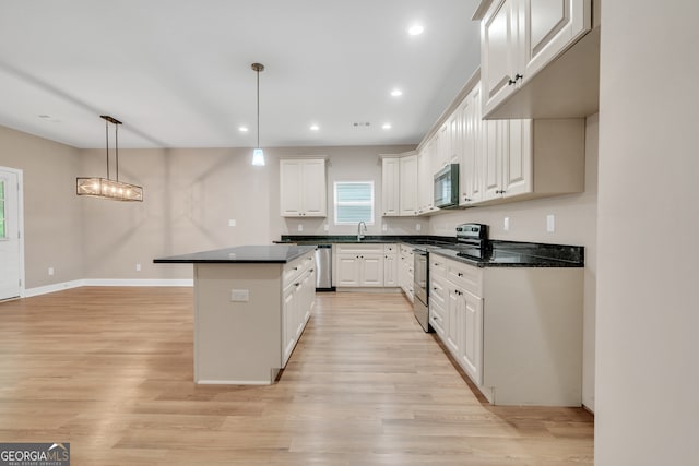 kitchen with stainless steel appliances, white cabinets, and decorative light fixtures