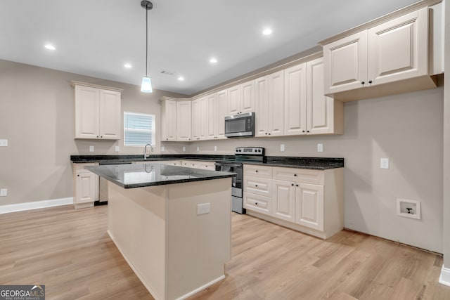 kitchen featuring a kitchen island, decorative light fixtures, white cabinetry, stainless steel appliances, and light hardwood / wood-style floors