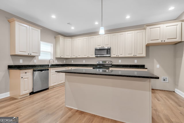 kitchen featuring light hardwood / wood-style flooring, a center island, appliances with stainless steel finishes, and hanging light fixtures