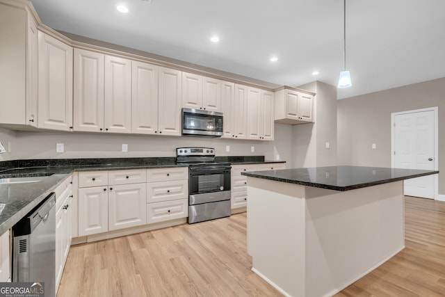 kitchen featuring light hardwood / wood-style floors, a center island, stainless steel appliances, decorative light fixtures, and dark stone countertops