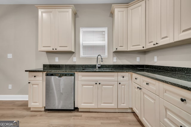 kitchen featuring light wood-type flooring, dark stone counters, dishwasher, and sink