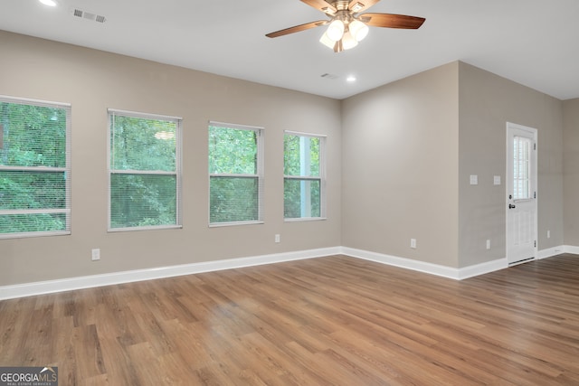 empty room with light wood-type flooring, a healthy amount of sunlight, and ceiling fan