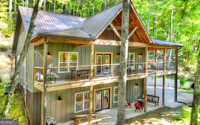 back of house with a patio, board and batten siding, central AC, metal roof, and a balcony