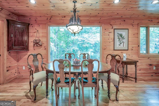 dining room with wood walls, wooden ceiling, and light hardwood / wood-style flooring