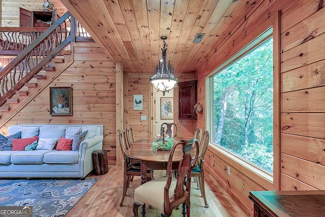 dining area featuring light hardwood / wood-style floors, wood walls, and wooden ceiling