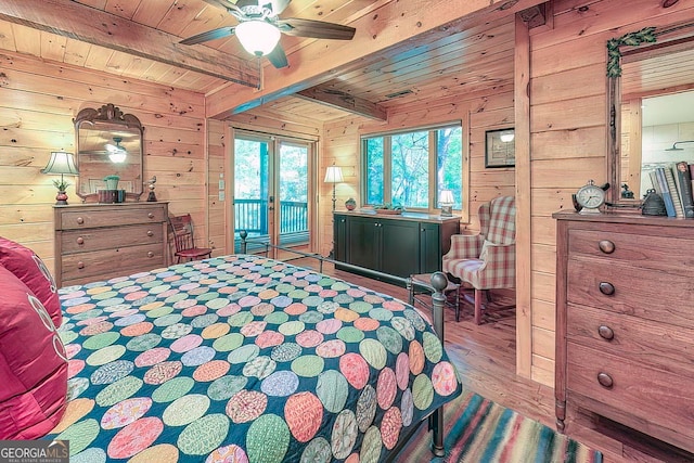 bedroom featuring access to outside, hardwood / wood-style floors, wooden walls, ceiling fan, and beam ceiling