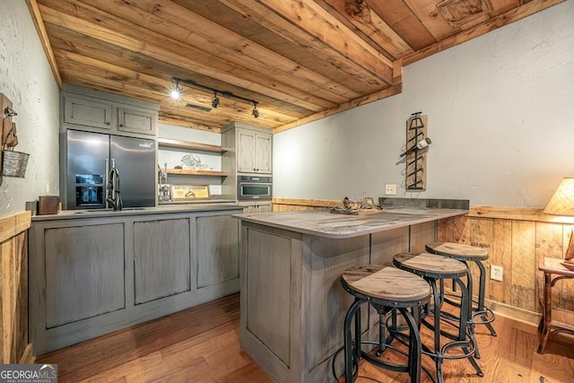 kitchen featuring wooden ceiling, wood finished floors, a peninsula, stainless steel appliances, and open shelves