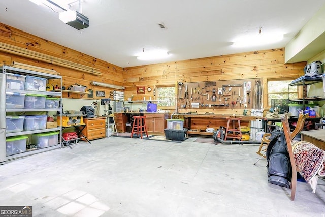 garage featuring wooden walls, a workshop area, and a garage door opener