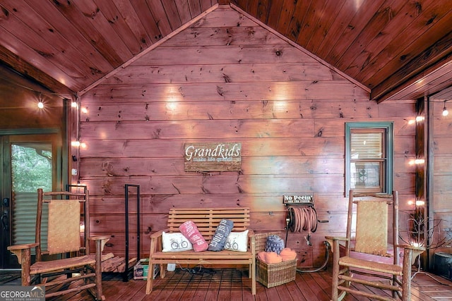 living area featuring wood walls, lofted ceiling, and wood ceiling