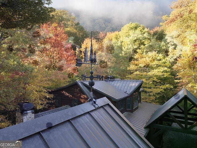 exterior space with a standing seam roof, metal roof, and a forest view