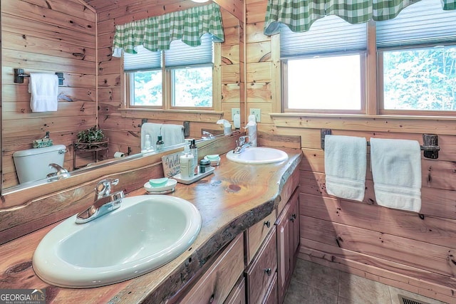 bathroom featuring toilet, vanity, wooden walls, and plenty of natural light