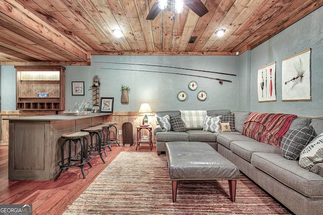 living room featuring wood ceiling, wooden walls, hardwood / wood-style flooring, ceiling fan, and indoor bar