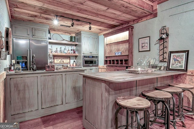 bar with rail lighting, wood ceiling, light hardwood / wood-style flooring, and appliances with stainless steel finishes