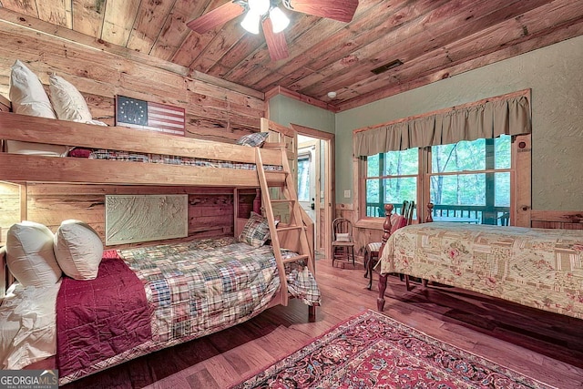 bedroom with wooden walls, hardwood / wood-style floors, wooden ceiling, and ceiling fan