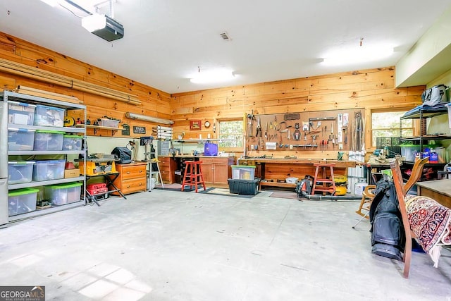 garage featuring a garage door opener, a workshop area, and wood walls