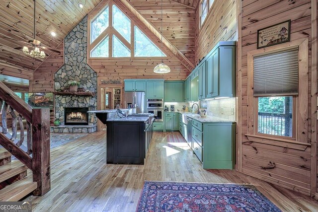 kitchen with appliances with stainless steel finishes, high vaulted ceiling, wood walls, light hardwood / wood-style floors, and wooden ceiling