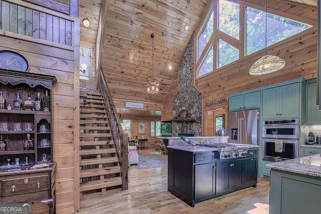 kitchen featuring light wood finished floors, wooden ceiling, light stone counters, stainless steel appliances, and wood walls