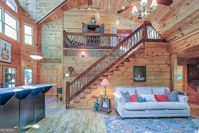 living room with wood walls, hardwood / wood-style flooring, wooden ceiling, high vaulted ceiling, and ceiling fan