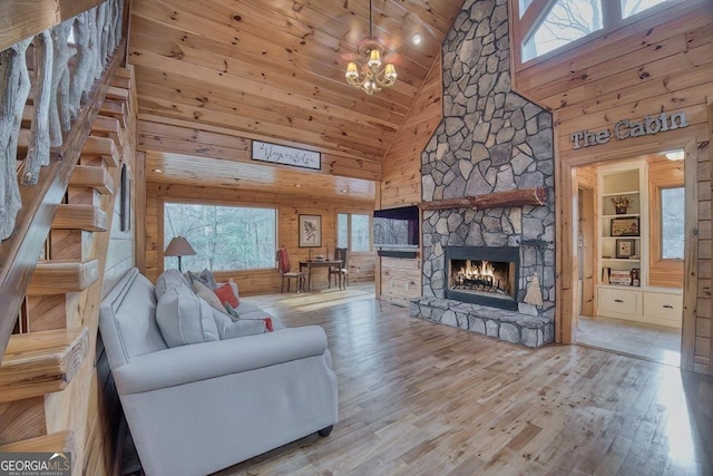 living room with wood walls, a notable chandelier, a fireplace, and wood finished floors