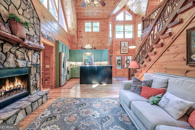 living room with high vaulted ceiling, wood walls, wood ceiling, and light hardwood / wood-style flooring