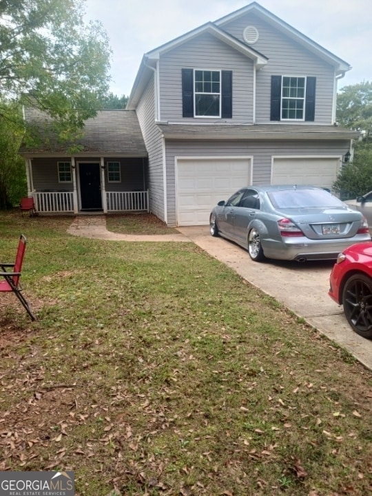 front of property with a porch, a garage, and a front lawn